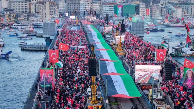 İstiklal Köprüsü'nde Türk bayraklarıyla coşkulu kalabalık, kutlama alanı.