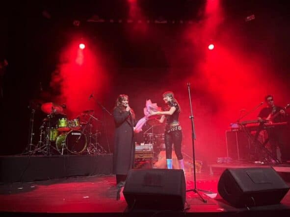 Sanatçı ve müzik grubu sahnede performans sergiliyor, konser ve etkinlik anı.